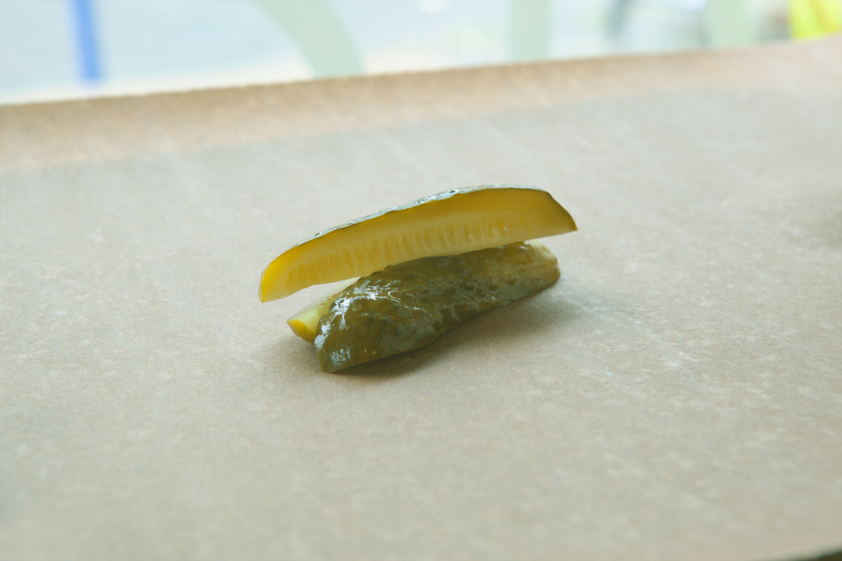 Close-up of two pickle slices on a light countertop, green and yellow tones
